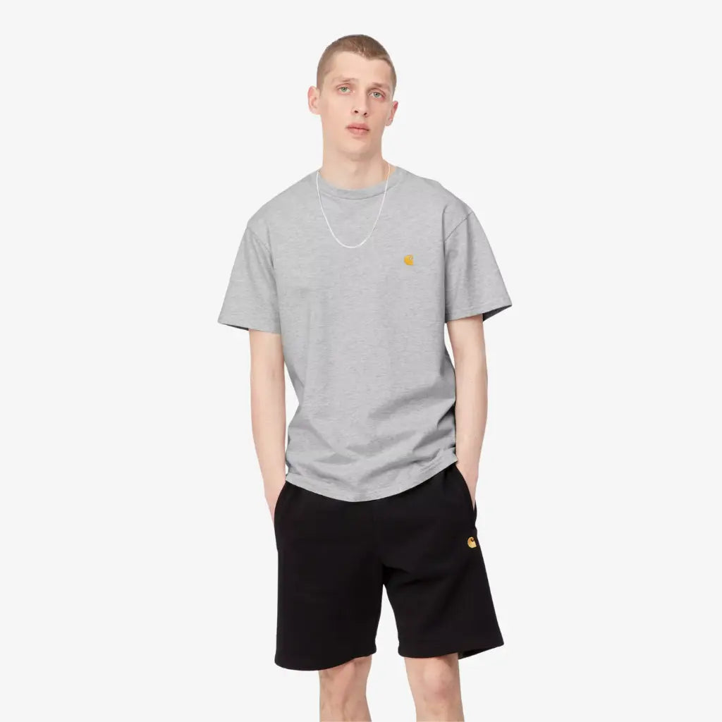 Homme portant le T-shirt Chase Carhartt WIP gris chiné de face, avec un short molleton noir à logo doré