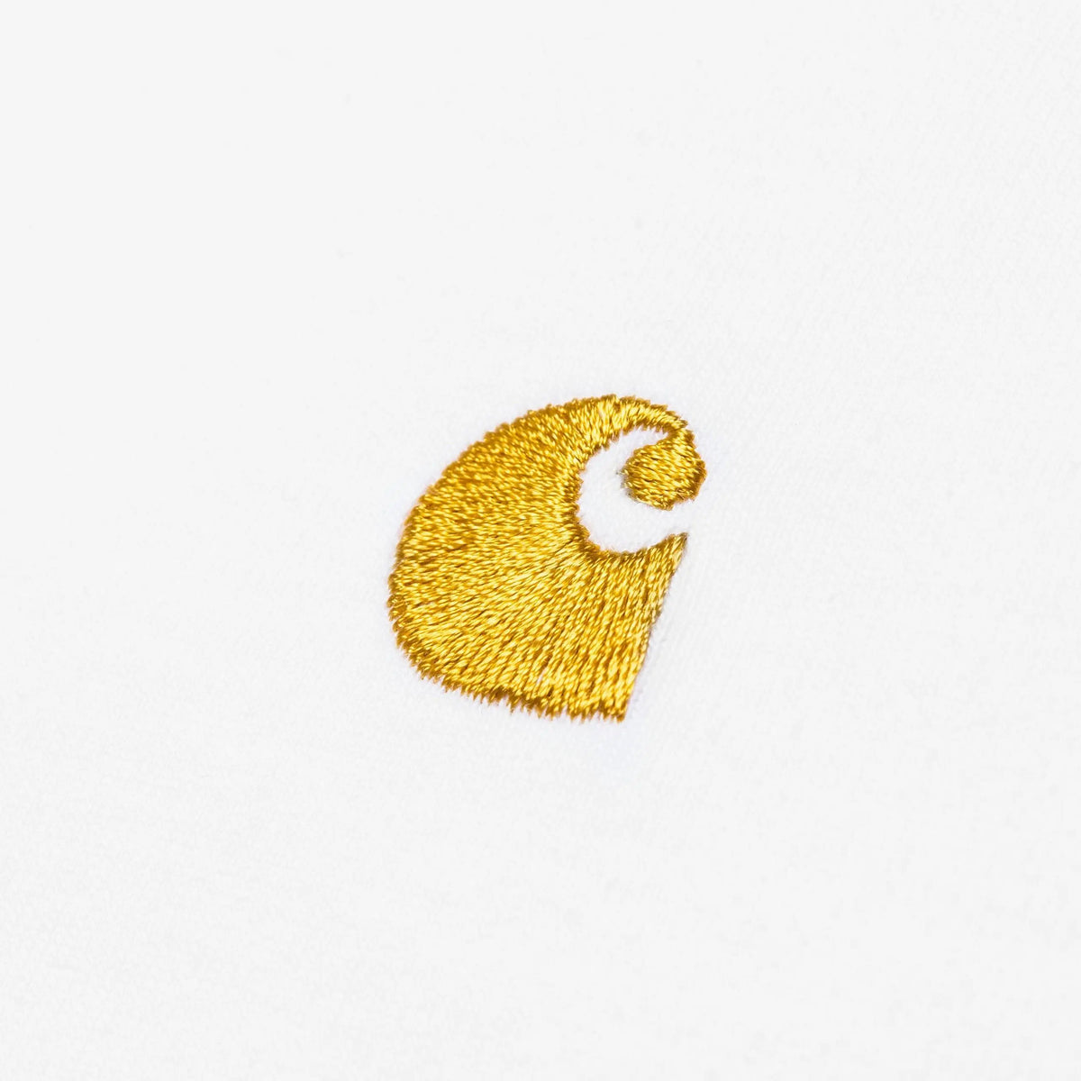 Gros plan du logo C Carhartt brodé fil doré sur le jersey blanc du T-shirt Chase