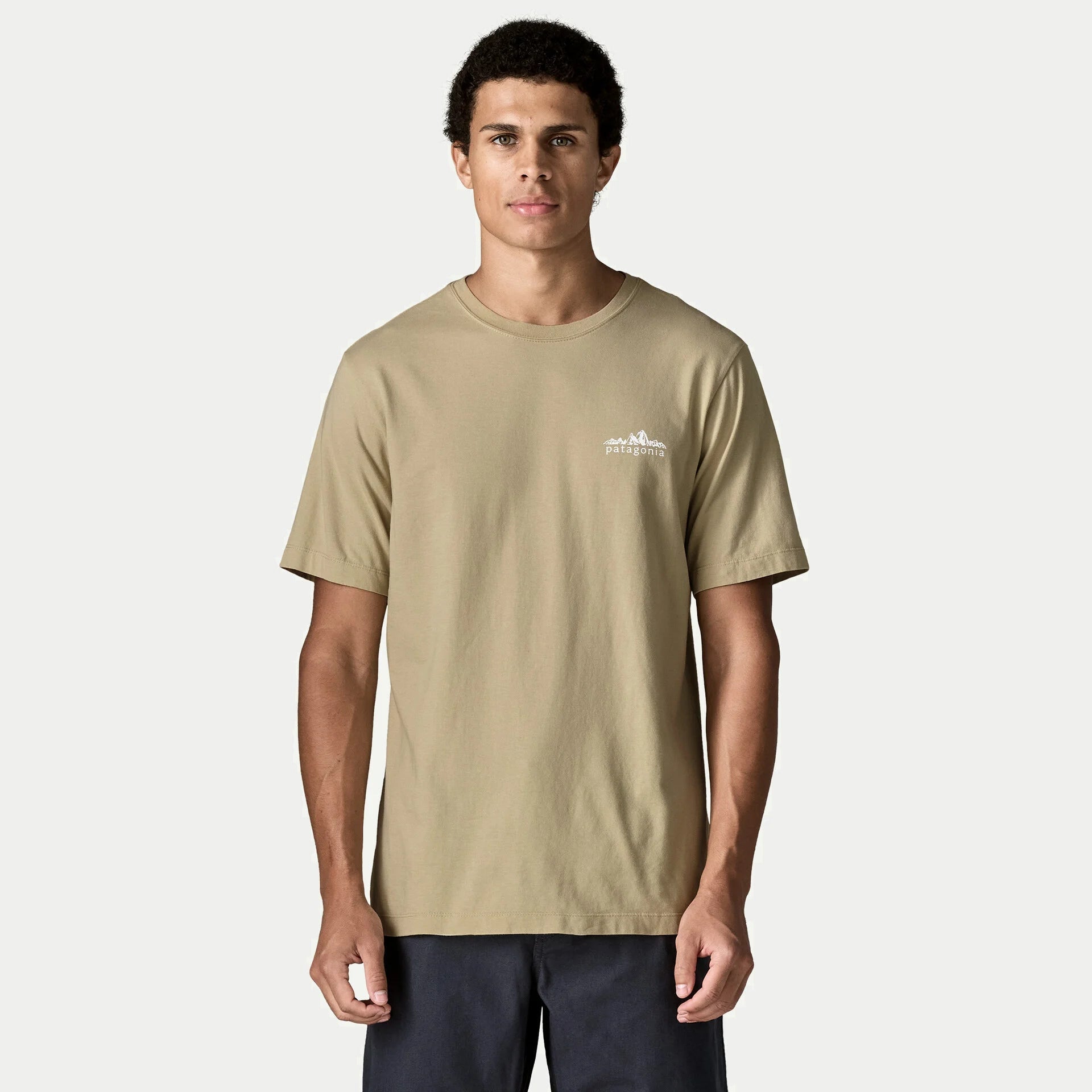 T-shirt Fitz Roy Foothills beige sable vu de face porté, petit logo montagne patagonia blanc sur la poitrine