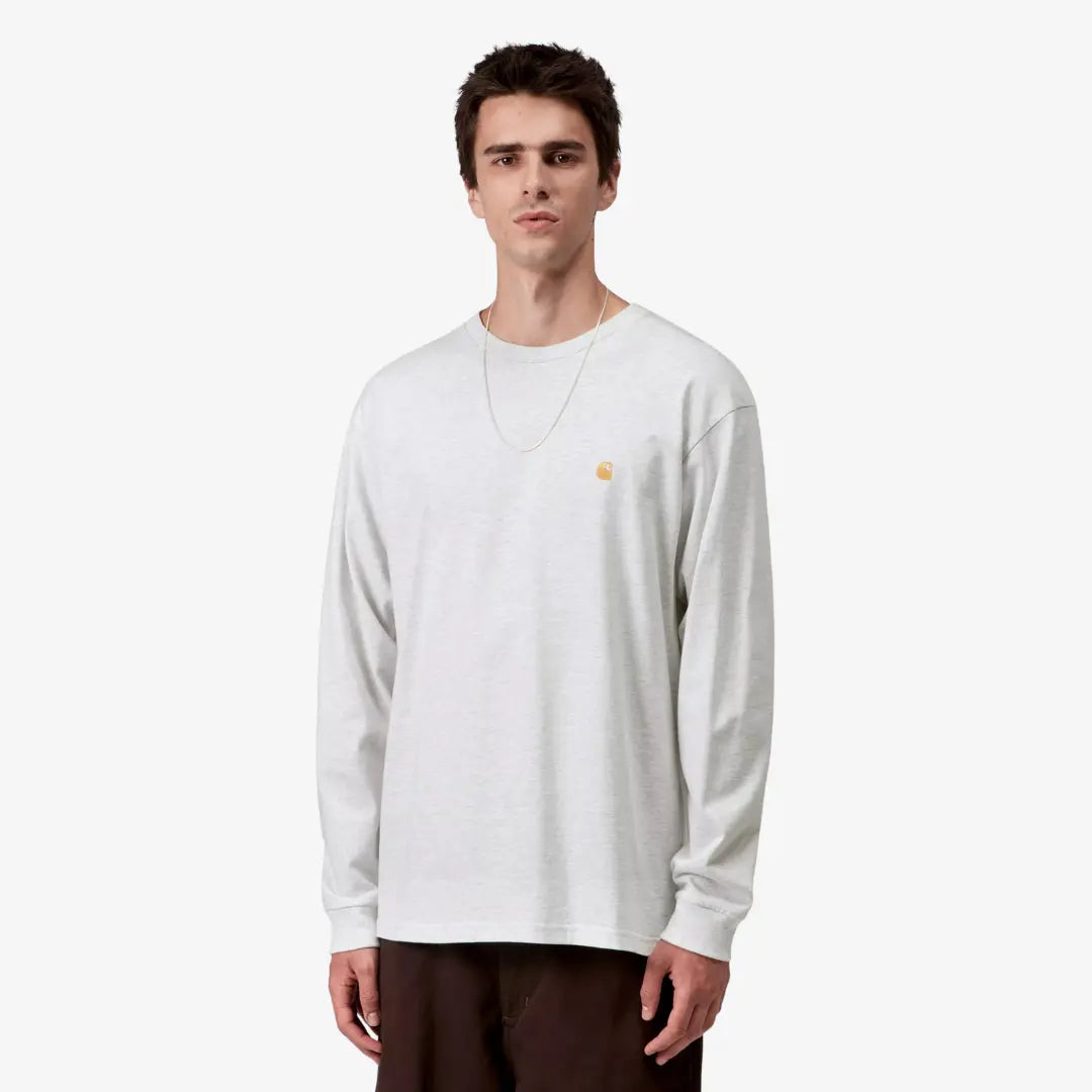 Homme portant le t-shirt manches longues Chase Ash Heather Carhartt WIP, coupe ample gris chiné clair, logo C doré