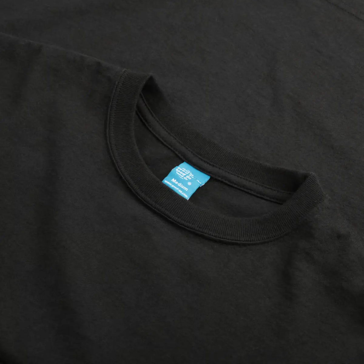 Encolure du T-shirt Good On noir en gros plan, étiquette de marque turquoise