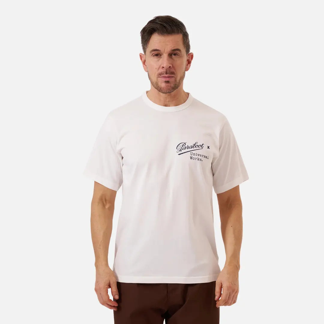 T-shirt blanc cassé porté de face, petit logo script bleu marine sur la poitrine droite