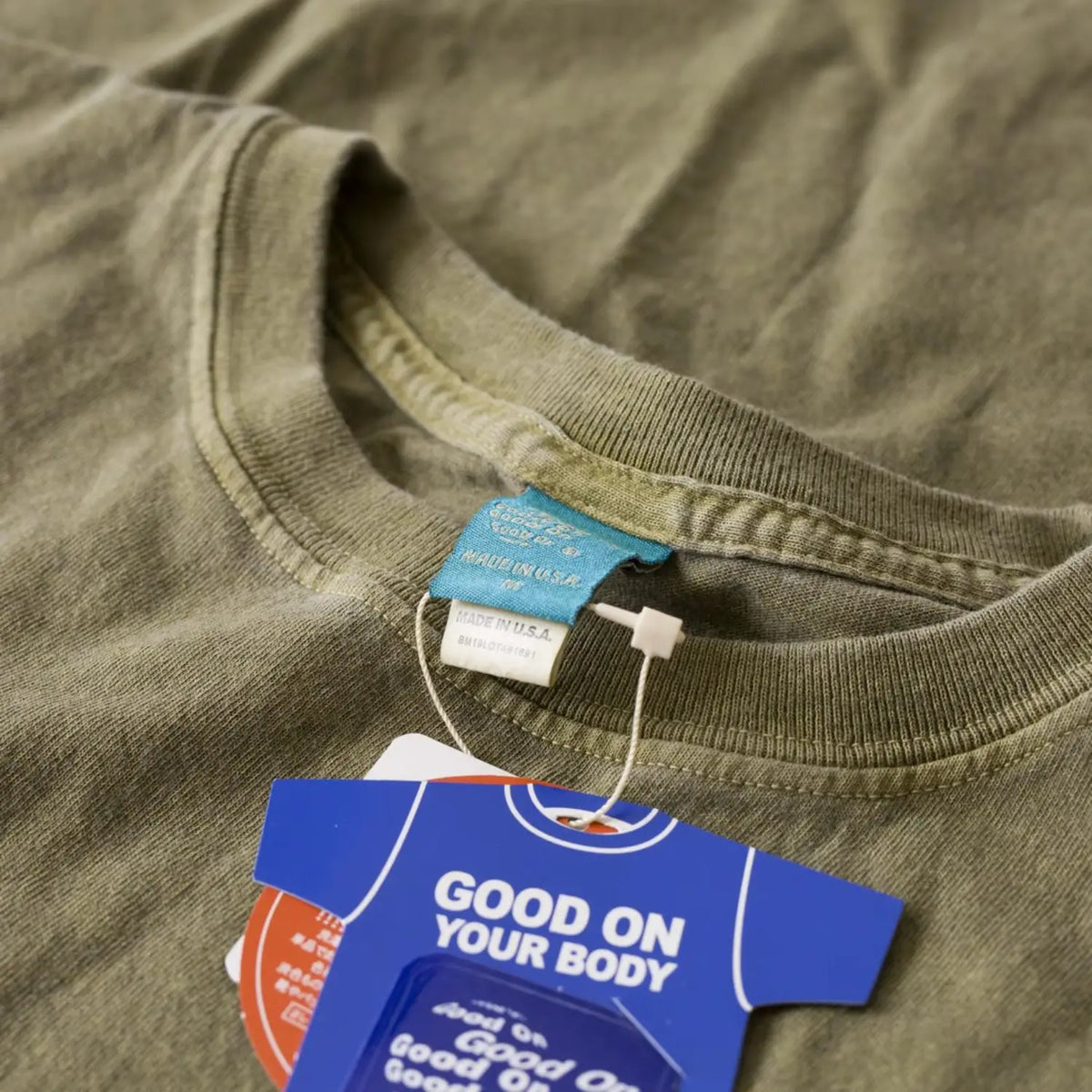 T-shirt Good On Sage vu de près à l'encolure, étiquettes tissée et carton visibles