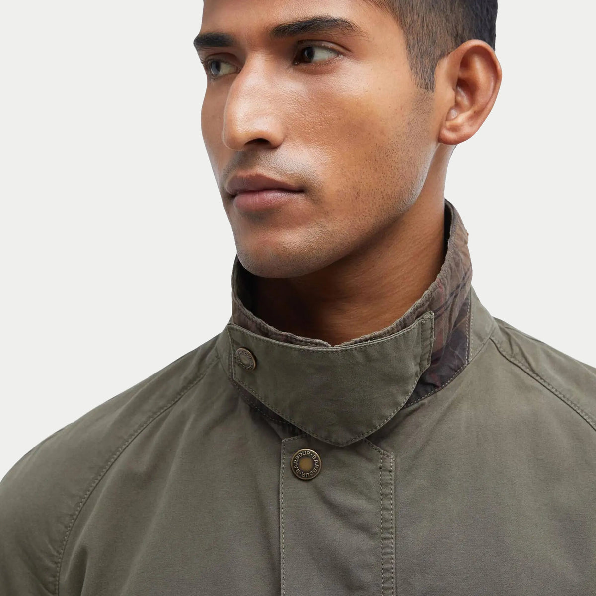 Gros plan du col en velours côtelé de la veste Ashby Casual Barbour Olive, patte à pression laiton gravée