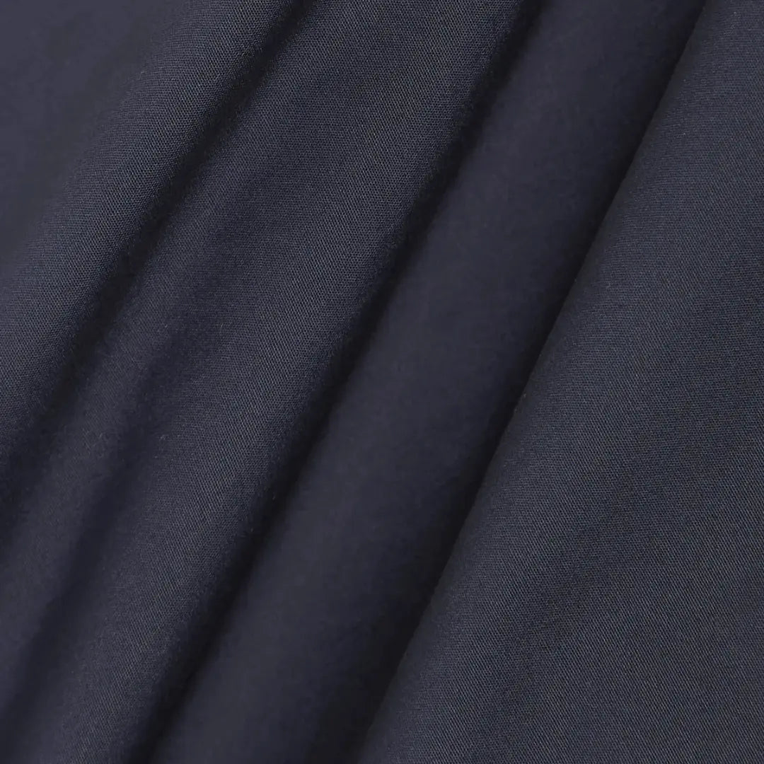 Macro du tissu bleu marine de la veste Bakers, toile de coton mate au drapé souple