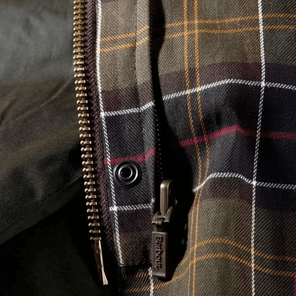 Détail de la doublure tartan Barbour et du zip laiton de la veste cirée Beaufort olive