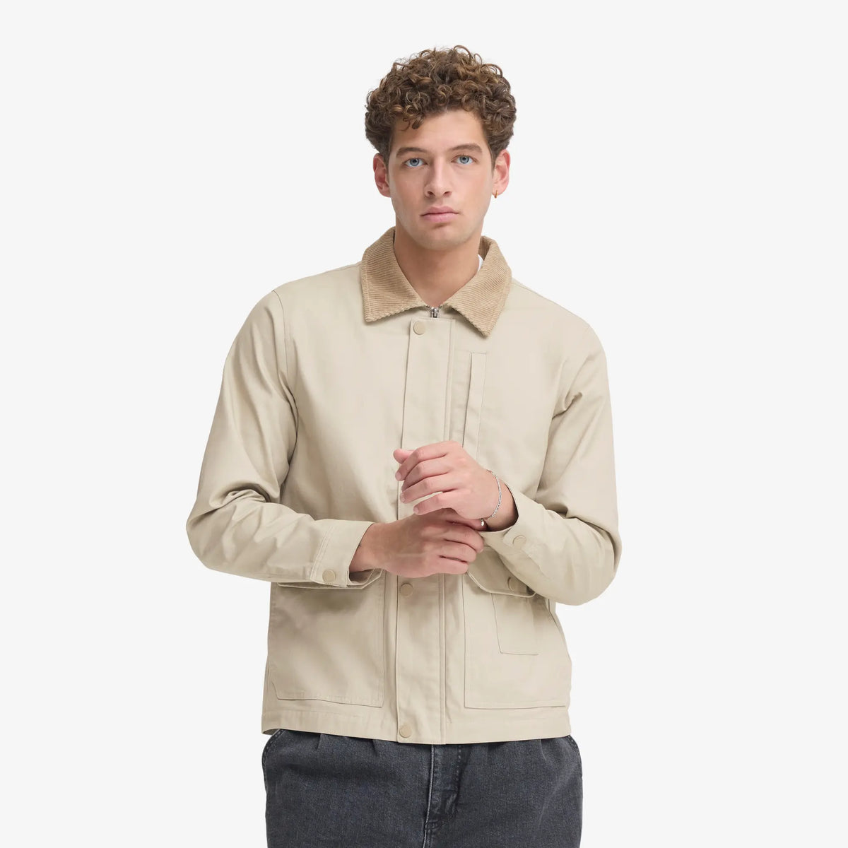 Veste en coton ciré beige portée ouverte sur un jean gris, zip et pressions ton sur ton