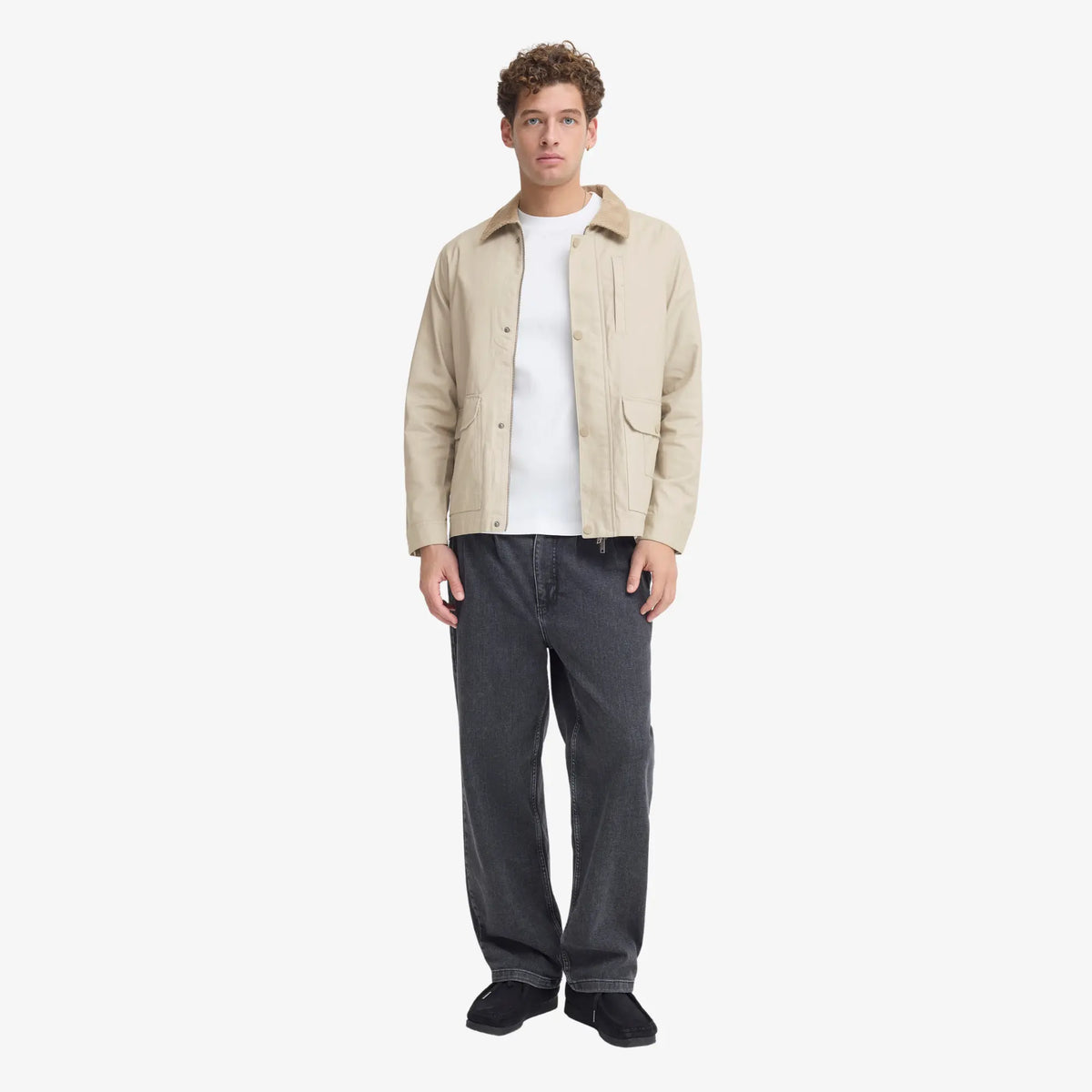 Silhouette complète : veste en coton ciré beige sur un t-shirt blanc et un jean gris