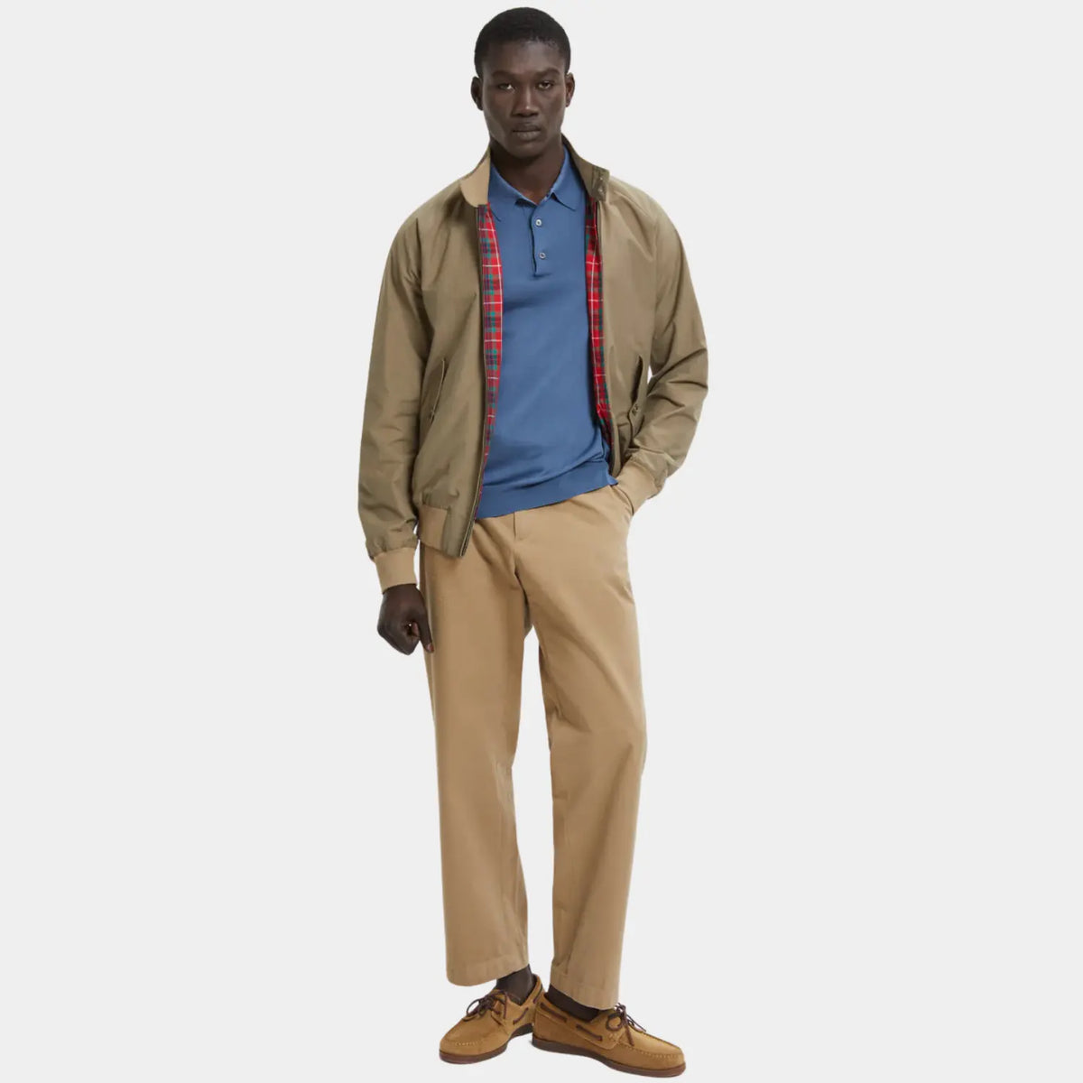 G9 Tan portée ouverte sur un polo bleu, revers tartan rouge apparents, avec un pantalon chino beige
