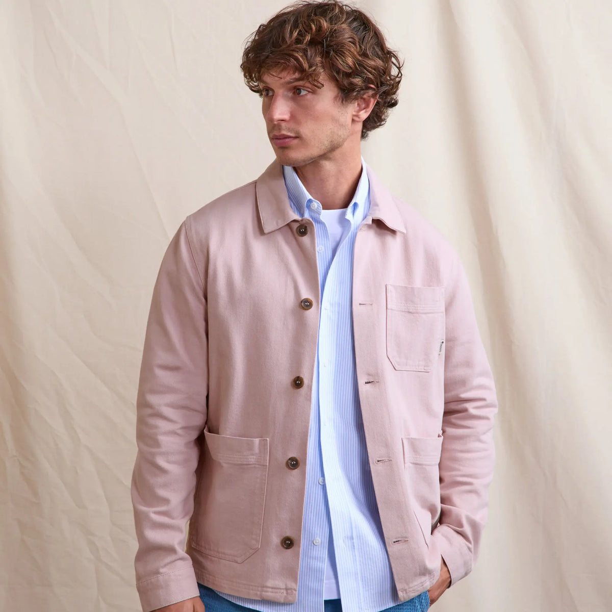 Veste Lorge rose portée ouverte sur une chemise rayée bleu ciel et un jean