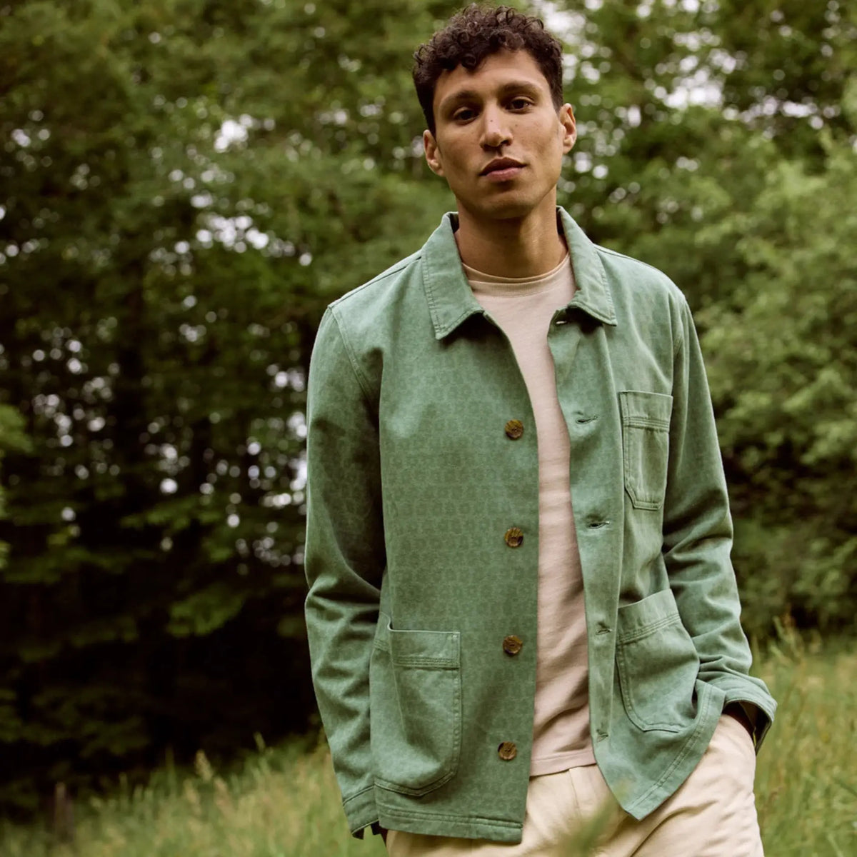 Veste Lorge verte portée ouverte en extérieur sur un t-shirt écru et un pantalon clair