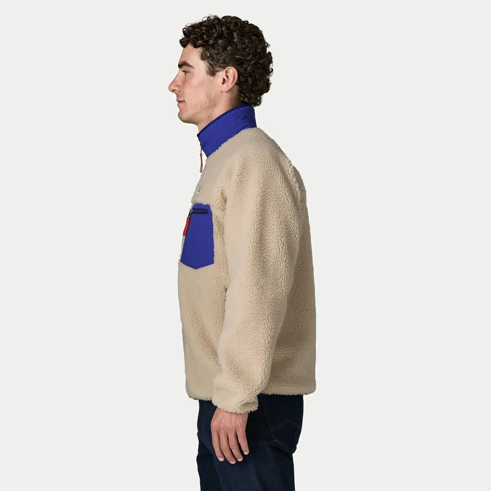 Veste polaire Retro-X Patagonia de profil, manche longue sherpa écru, poche poitrine nylon cobalt et tirette rouge