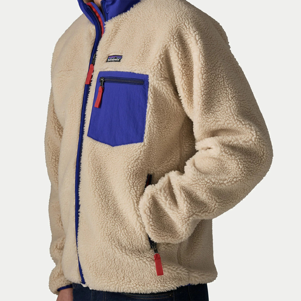 Veste polaire Retro-X Patagonia en gros plan trois quarts, zip cobalt, poche poitrine et poche latérale à tirettes rouges