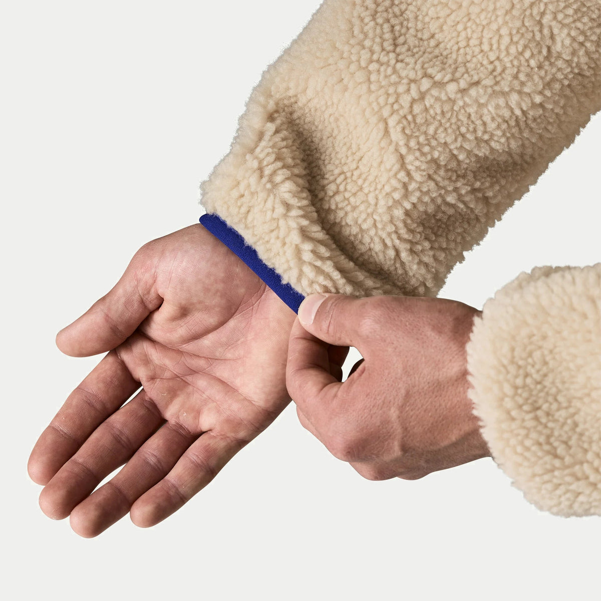 Détail du poignet de la veste polaire Retro-X Patagonia, manche sherpa écru soulignée d’un liseré nylon cobalt