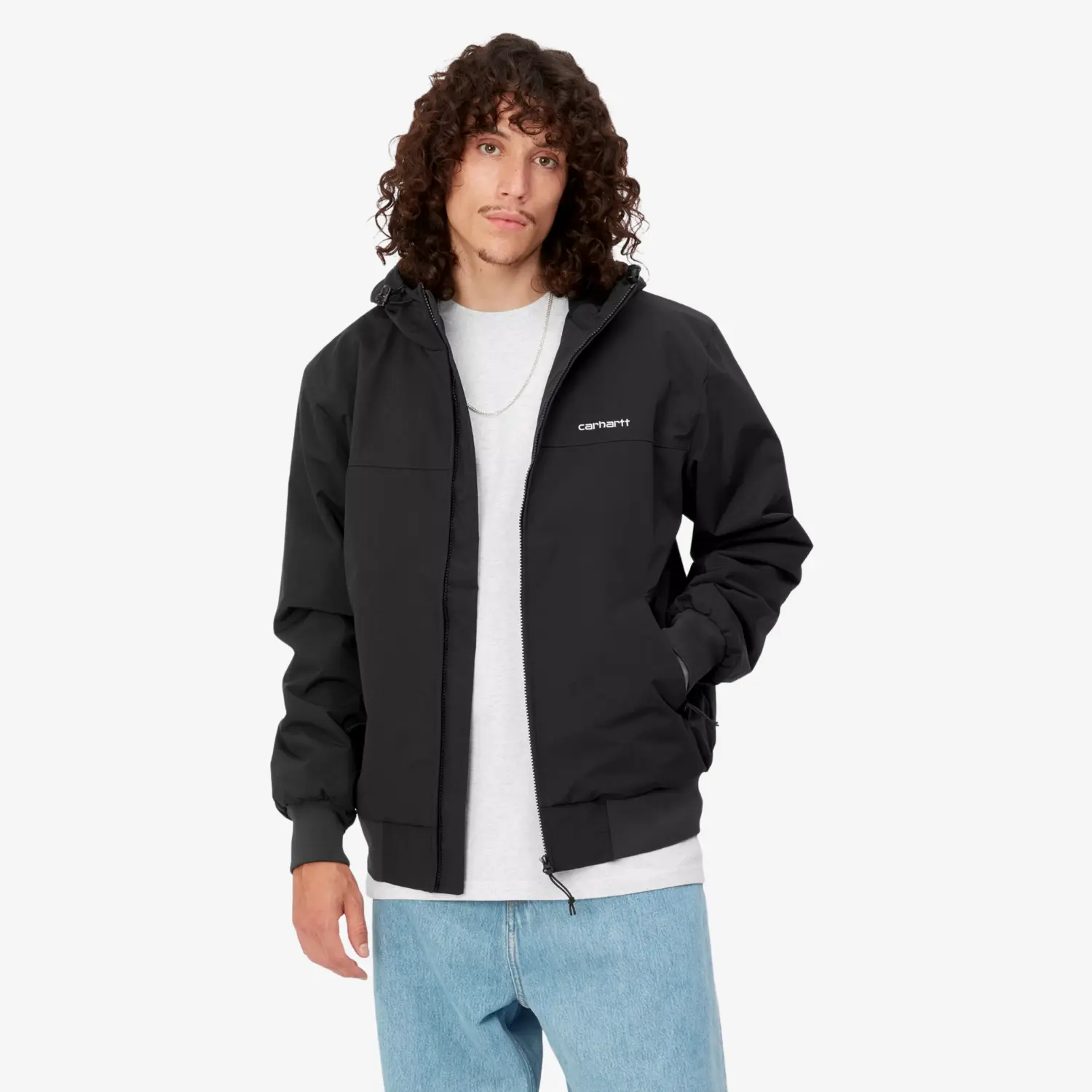 Homme portant la veste Sail Carhartt WIP noire ouverte sur un t-shirt blanc et un jean clair