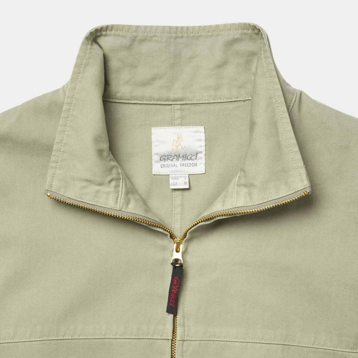 Veste Twill Around Dried Sage Gramicci - détail du col montant, étiquette Original Freedom et tirette rouge logotée