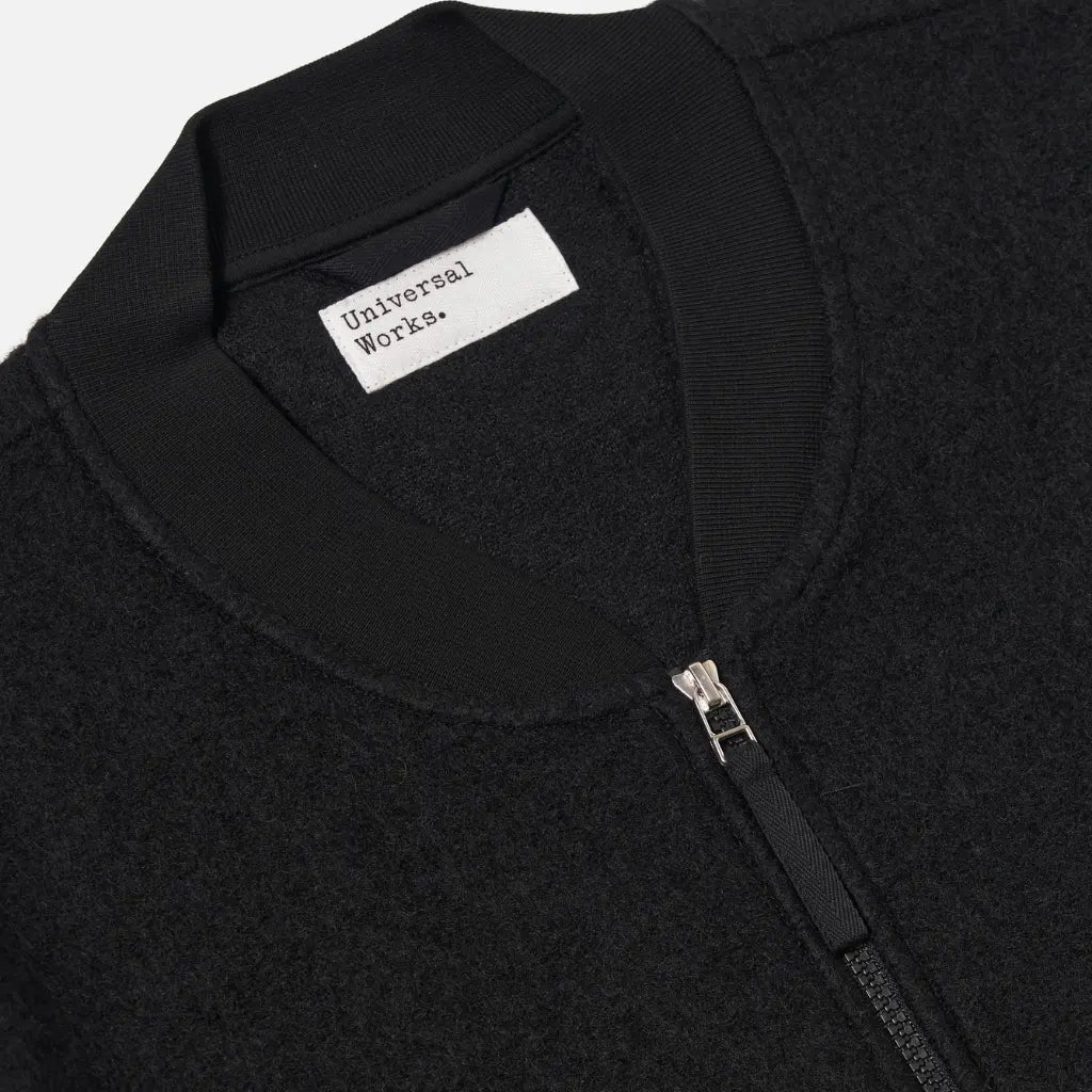 Col côtelé du Zip Bomber noir avec l'étiquette Universal Works et le curseur haut du zip