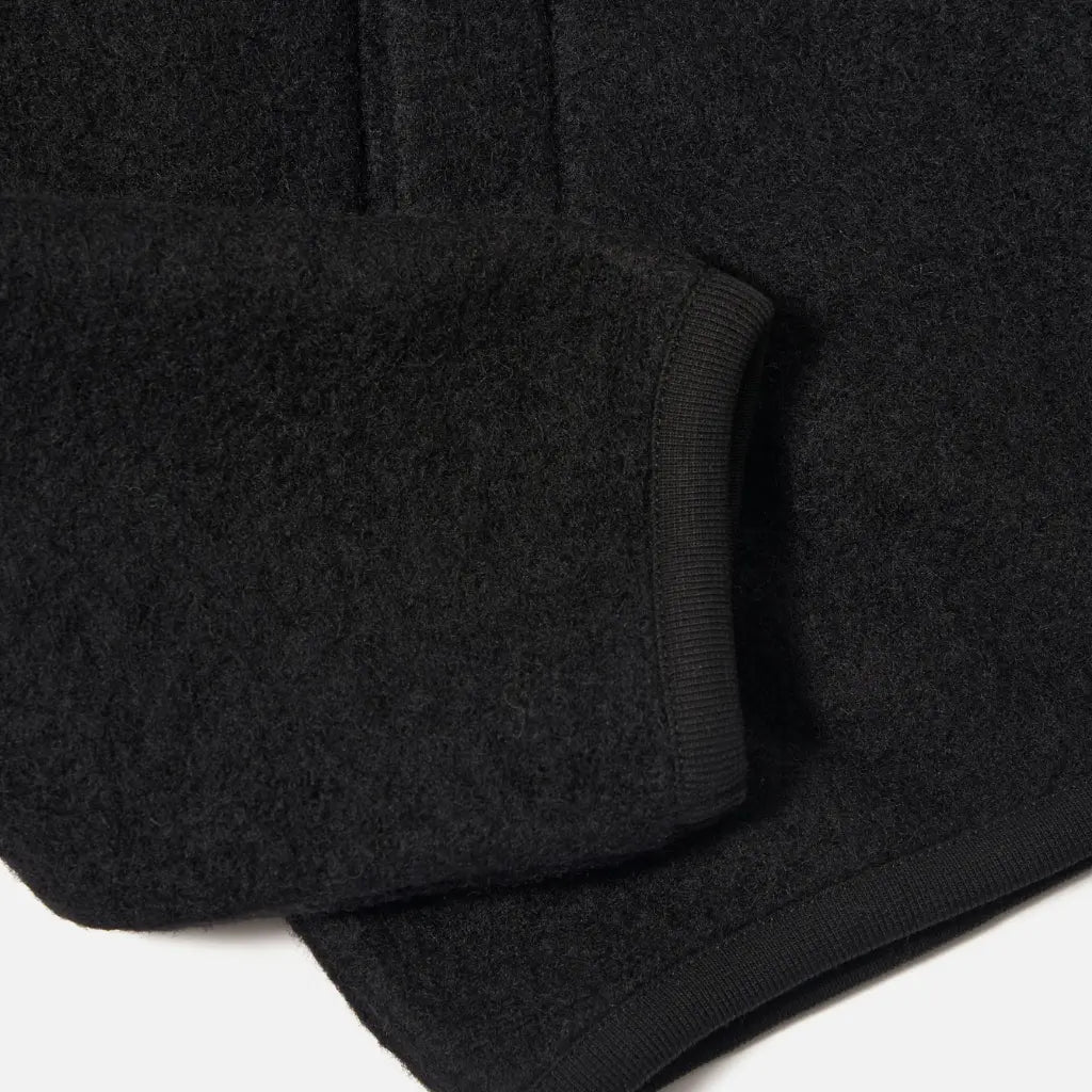 Poignet côtelé, poche passepoilée et bas côtelé du Zip Bomber en laine noire